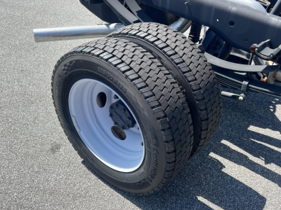 Ford F-450 cab chassis wheel assembly showing dual rear tires and white steel wheel with treaded tires.