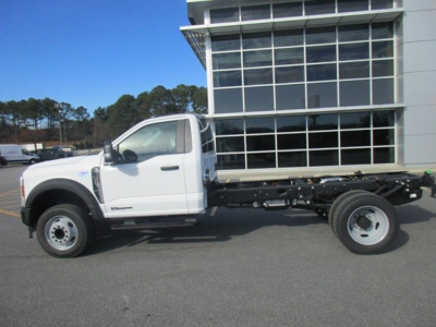 Ford F-450 cab and chassis truck side profile showing single cab and bare frame in white, with front wheels and rear dual wheels, dealership lot in background.