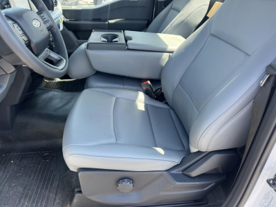 Front interior of a 2026 Ford F-450 cab and chassis showing gray cloth seats, center console, and steering wheel.