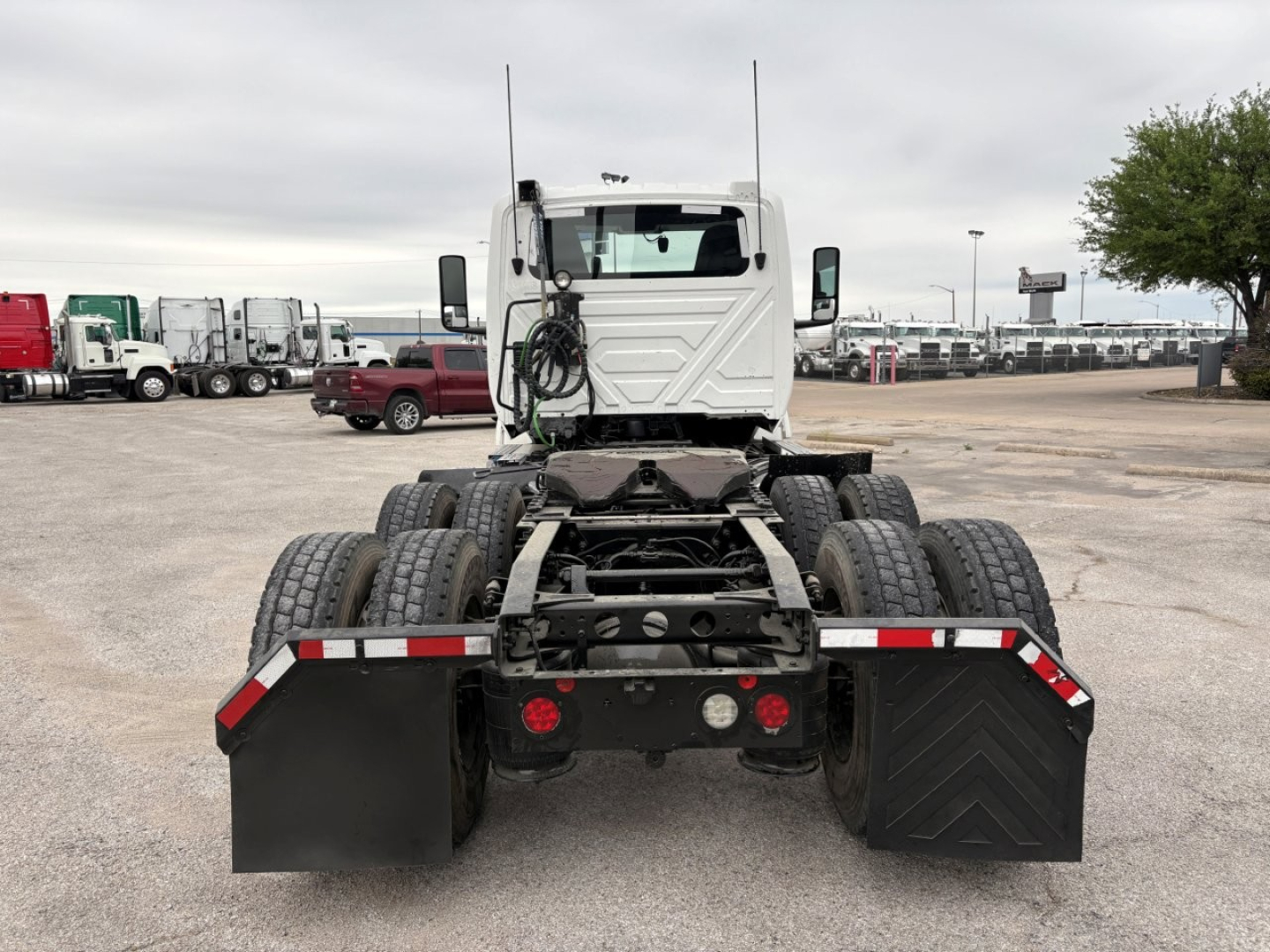 Vehicle rear view of a cabless tractor on a lot showing dual rear axles and mudflaps with reflective markings.