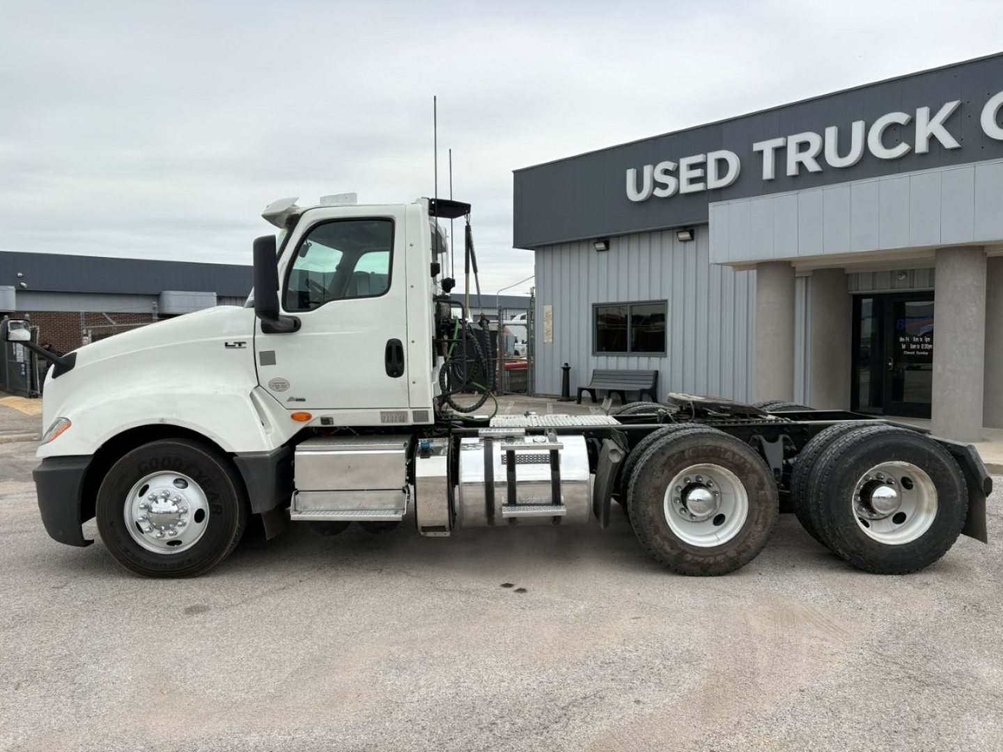 Truck side view of a white 2019 International LT conventional daycab, showing cab and chassis with fuel tanks and dual rear axles, at a used truck lot.