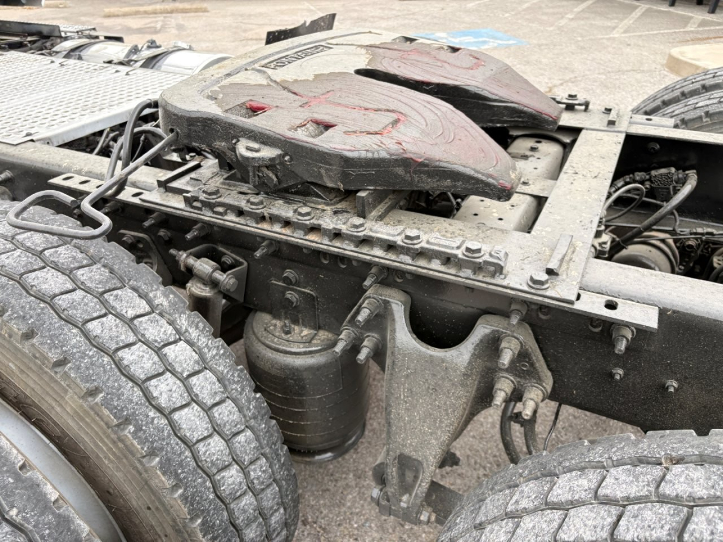 Chassis area of a 2019 International LT daycab showing seat, mounting brackets, air tanks, and surrounding hardware near the cab. Visible components include air lines, tank, and frame members.