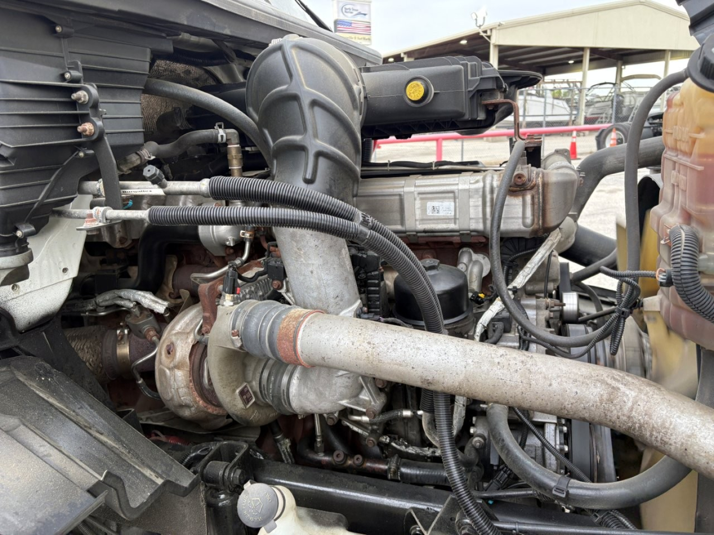Engine bay view of 2019 International LT showing turbo, intake, hoses, and coolant reservoir cap visible.