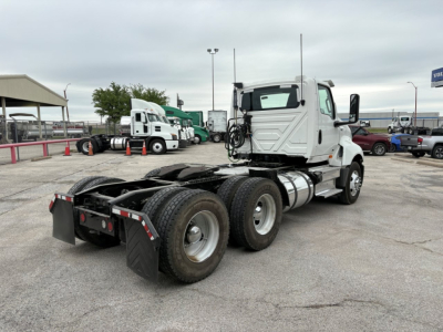 Truck chassis view of a 2019 International LT daycab, chassis with triple rear axles, white cab, hoses and fittings near cab, stock number B3113P, showing wheels and fifth wheel area.