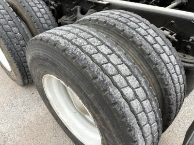 Truck wheel and dual rear tires showing tread and rim with undercarriage components in view.