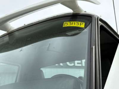 Vehicle windshield with B3113P stock tag on a 2019 International LT conventional daycab truck cab-side view.