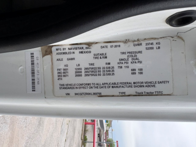 Label on door jamb with VIN, stock number, and GVWR details for a 2019 International LT Daycab truck. Text includes MFG BY NAVISTAR INC, MEXICO assembly, axle GAWR, tire sizes, TIRE PRESSURE, and vehicle safety standards. VIN 3HCDZTZR0KL369