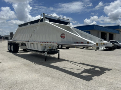 Dump trailer with white body, front hopper and long angled side panels, dual rear axles and landing legs visible; No slack sheets label on image?