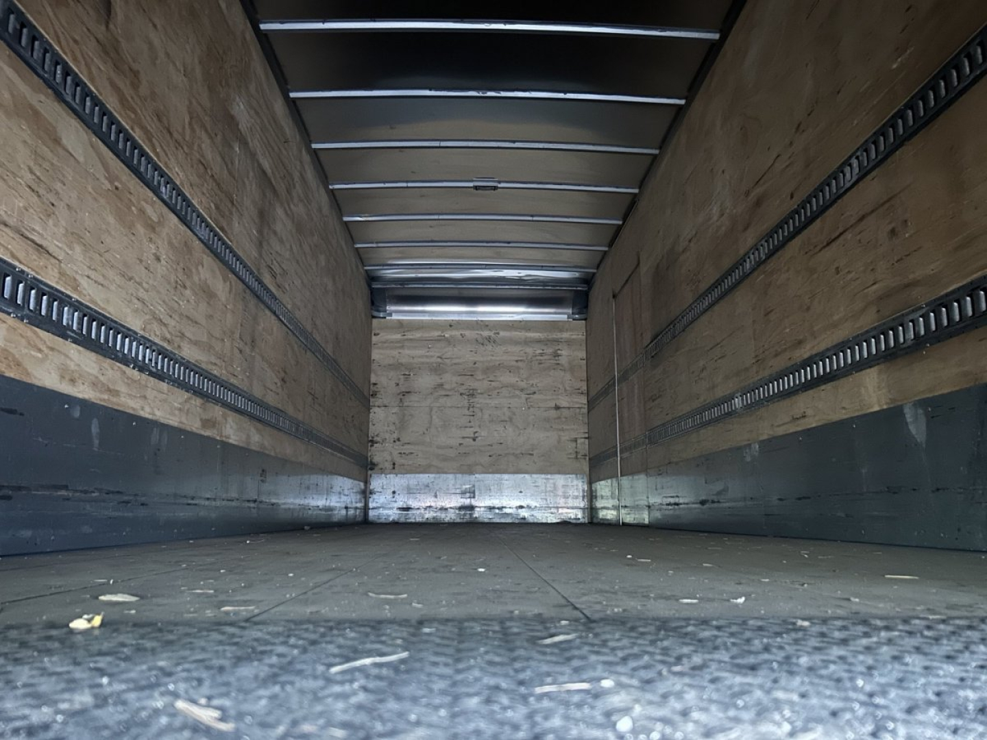 Truck cargo area of a 2019 Hino 268 in a box van showing empty wooden sidewalls and metal rails.