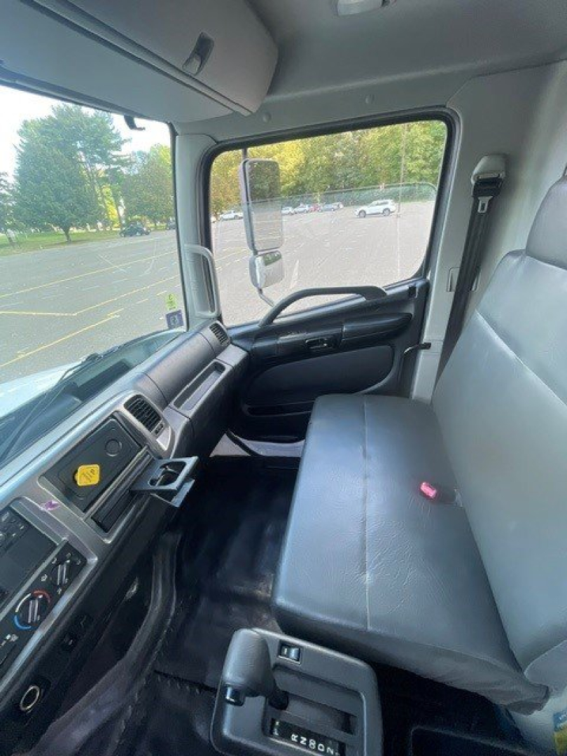 Cab interior of 2019 Hino 268 truck showing driver seat, steering wheel, dashboard controls, and bench passenger seat.