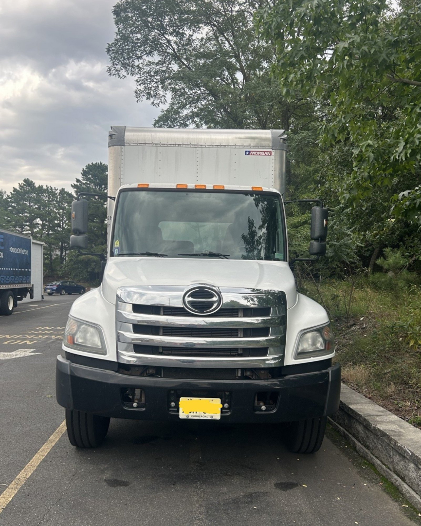 Front view of a white 2019 Hino 268 box truck showing large chrome grille, Hino emblem, and rectangular cargo box; black bumper and mirrors visible.
