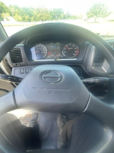 Steering wheel and dashboard of a 2019 Hino 268 box van truck interior showing instrument cluster and steering column with stalk controls.