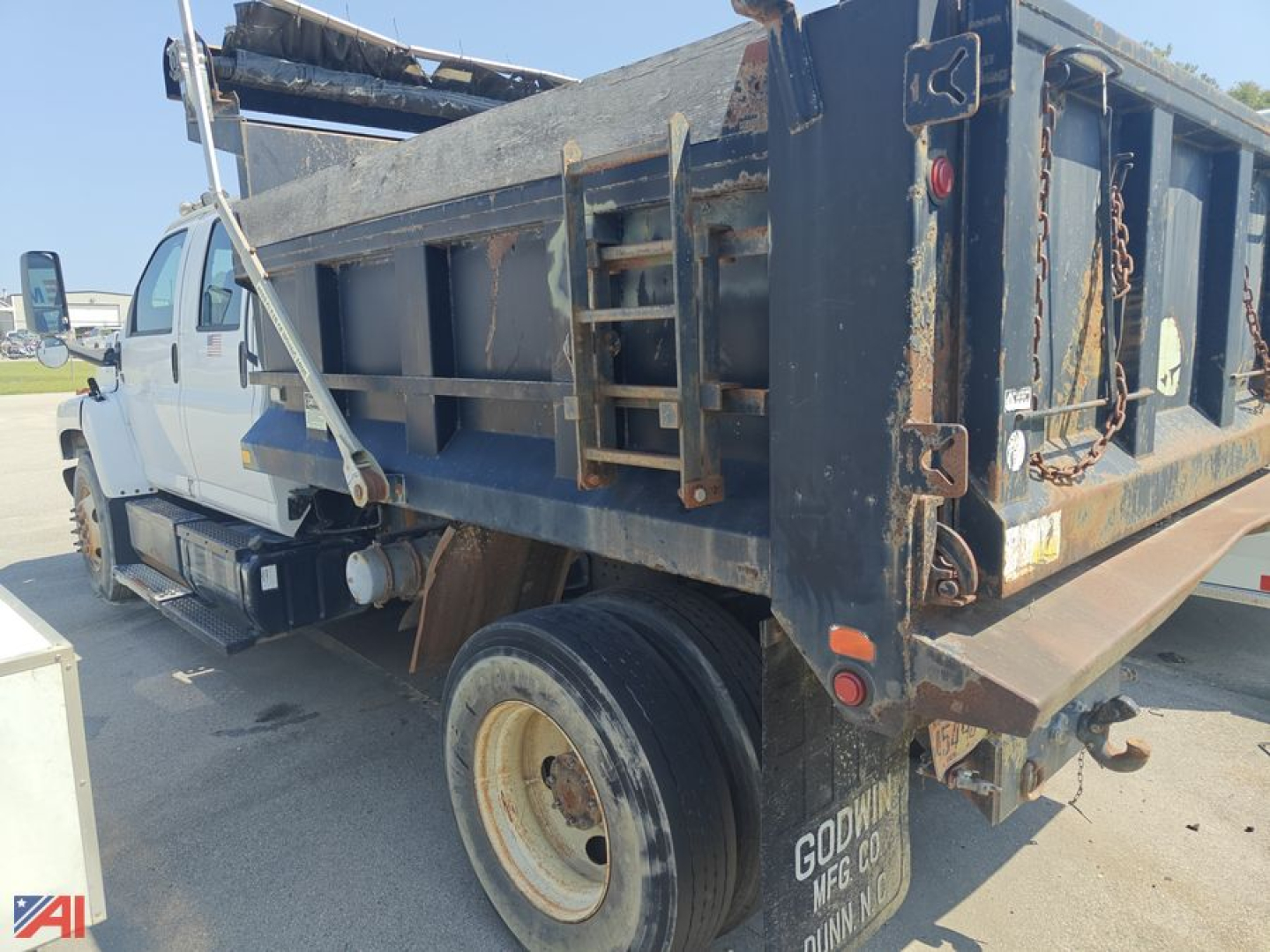Dump truck bed and rear section of a 2005 Chevrolet C85000 dump truck showing metal dump bed, wheel, and tailgate area with chain latches.