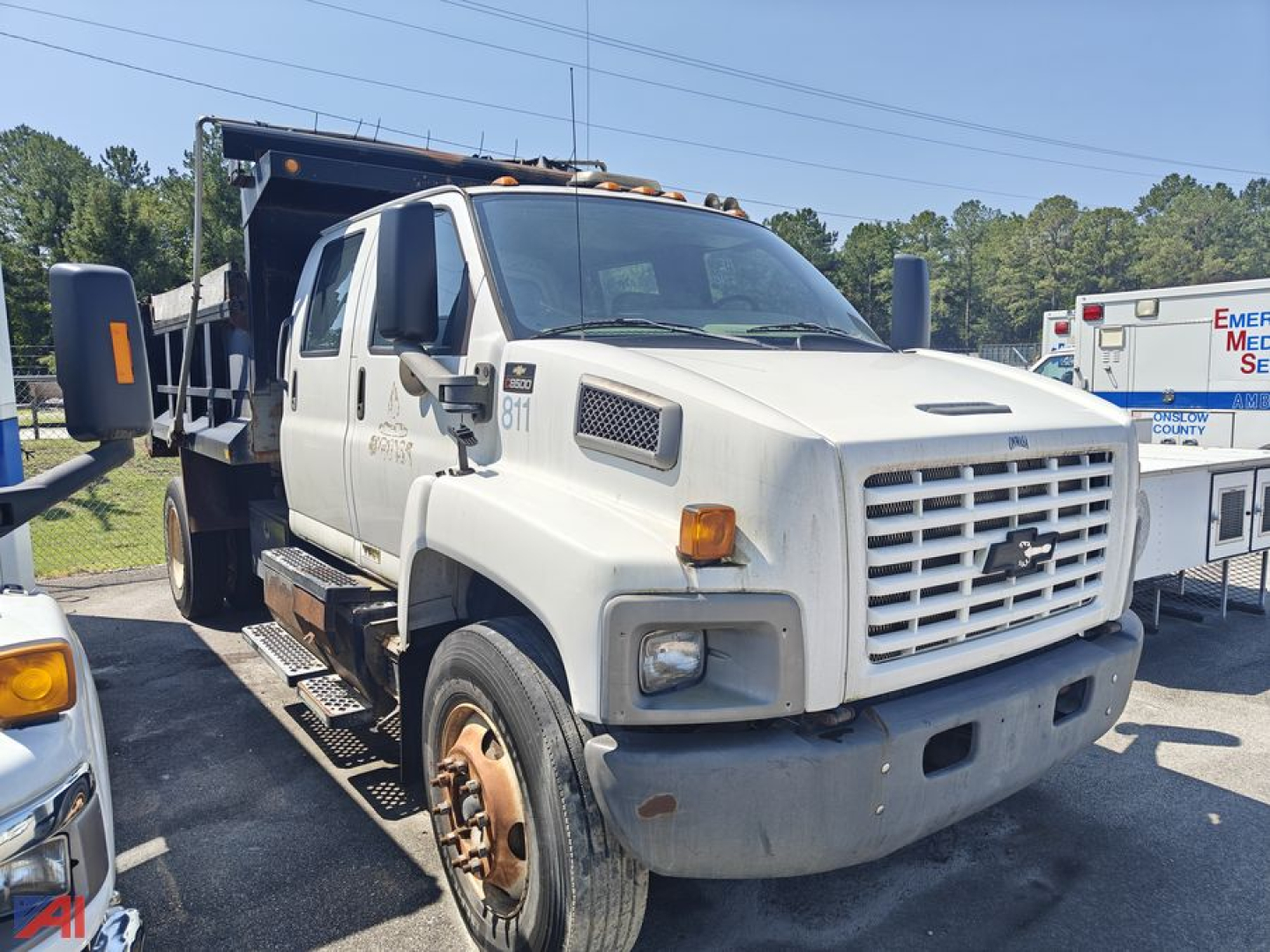 Dump truck cab in-service showing front grille and wheel wells with Chevrolet emblem, heavy-duty bumper, and side mirrors.
