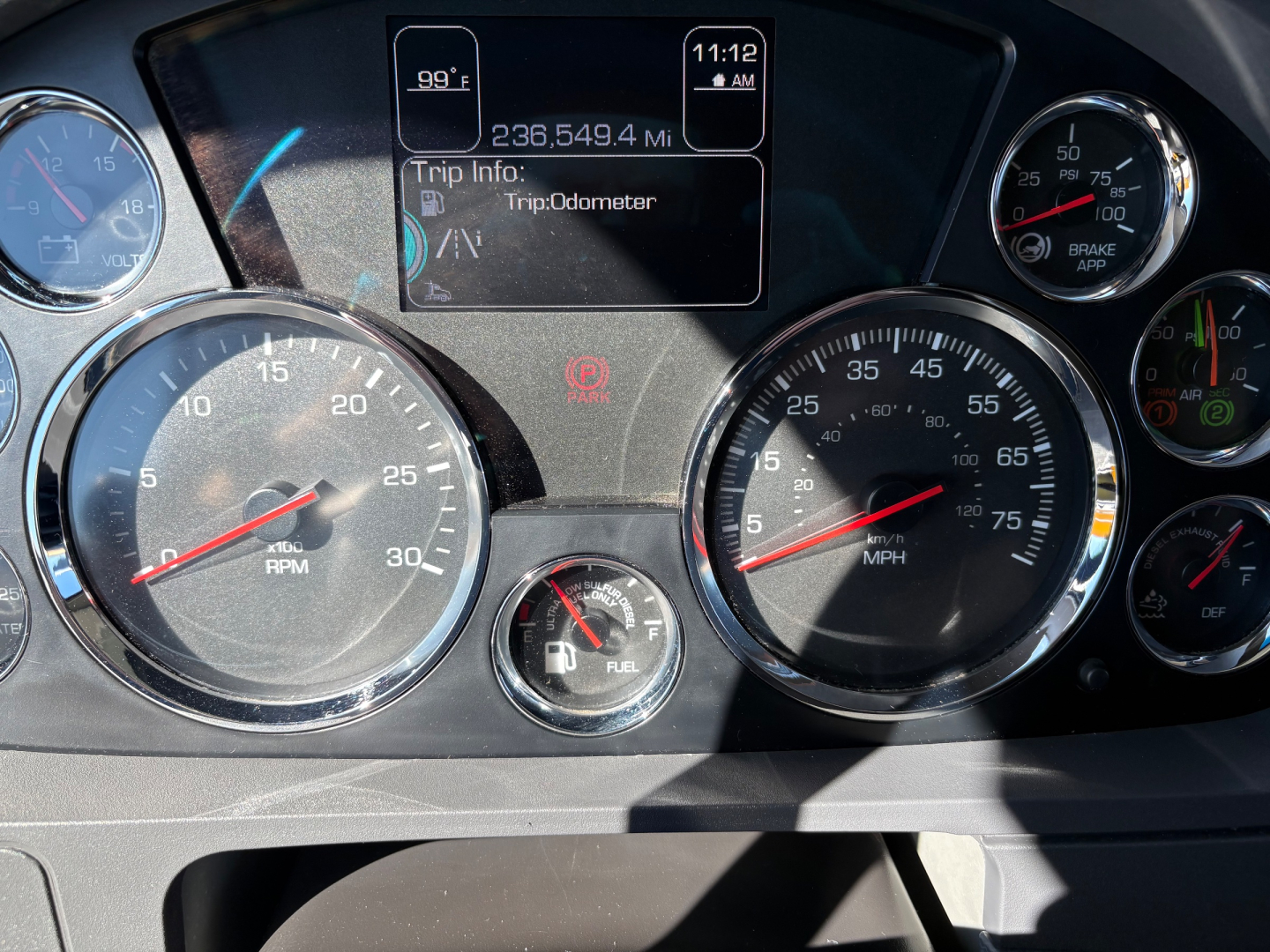 Kenworth T680 dashboard showing multiple gauges, digital trip info on center display, odometer reading, and fuel gauge.