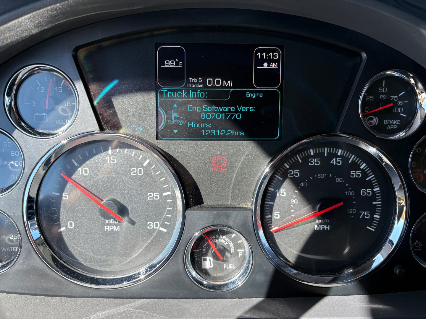 Kenworth truck instrument cluster showing digital trip info screen and gauges with rpm and speed dials in dashboard.