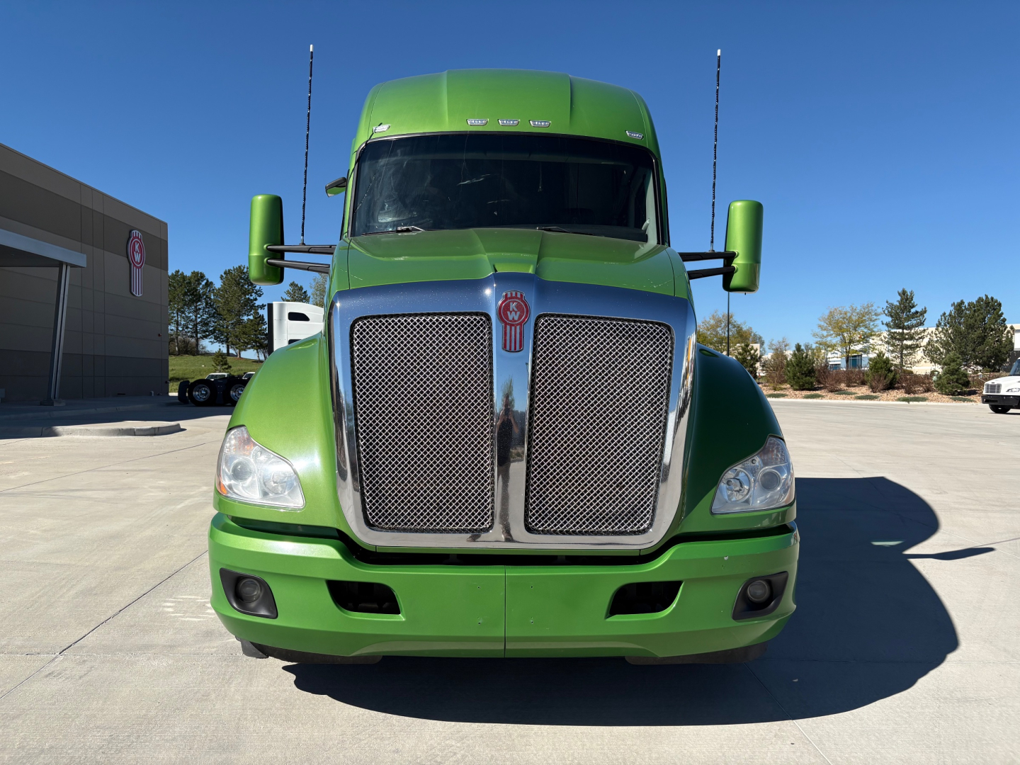 Front view of a green 2020 Kenworth T680 truck showing large chrome grille with Kenworth emblem, headlights, and side mirrors.
