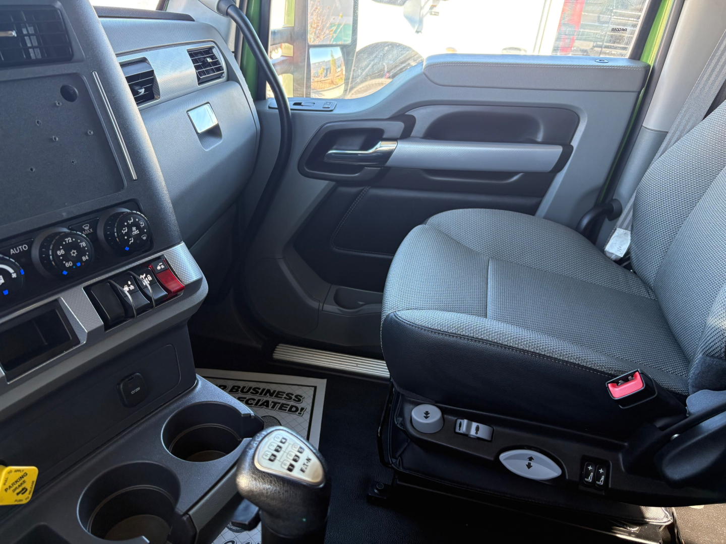 Kenworth T680 cab interior showing driver seat with control switches, gear shifter, and dashboard gauges. VIN 1XKYD49X7LJ400252 visible; stock 0632808; conventional sleeper truck interior.