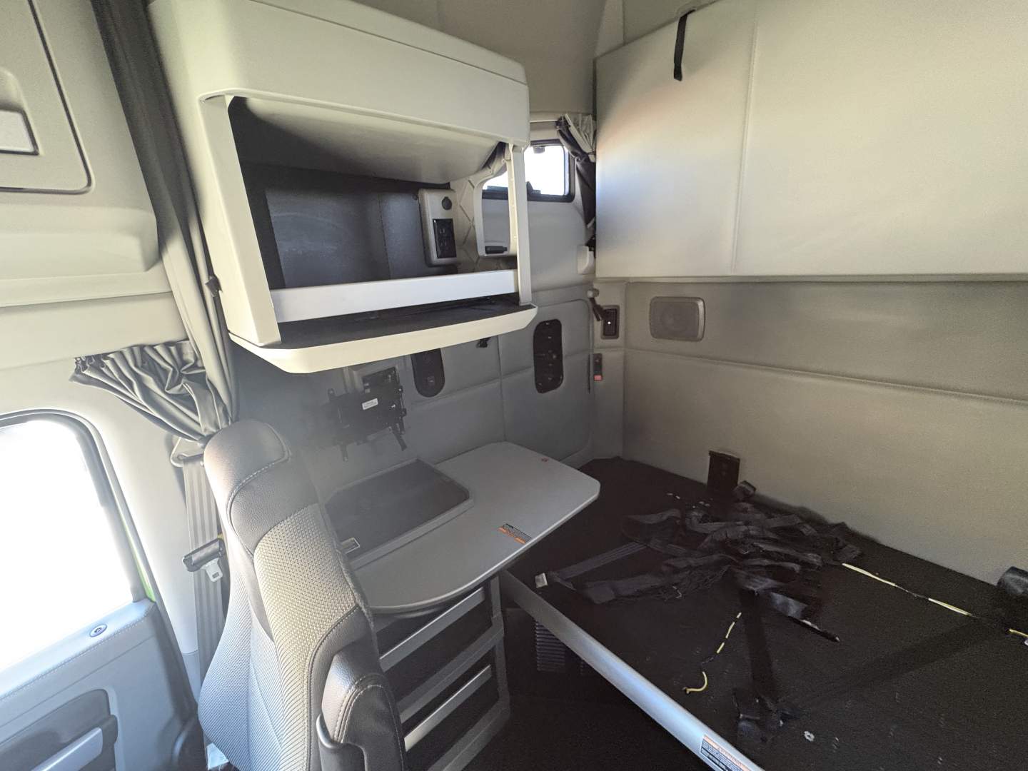 Kenworth T680 cab interior visible with sleeper area and storage compartments.