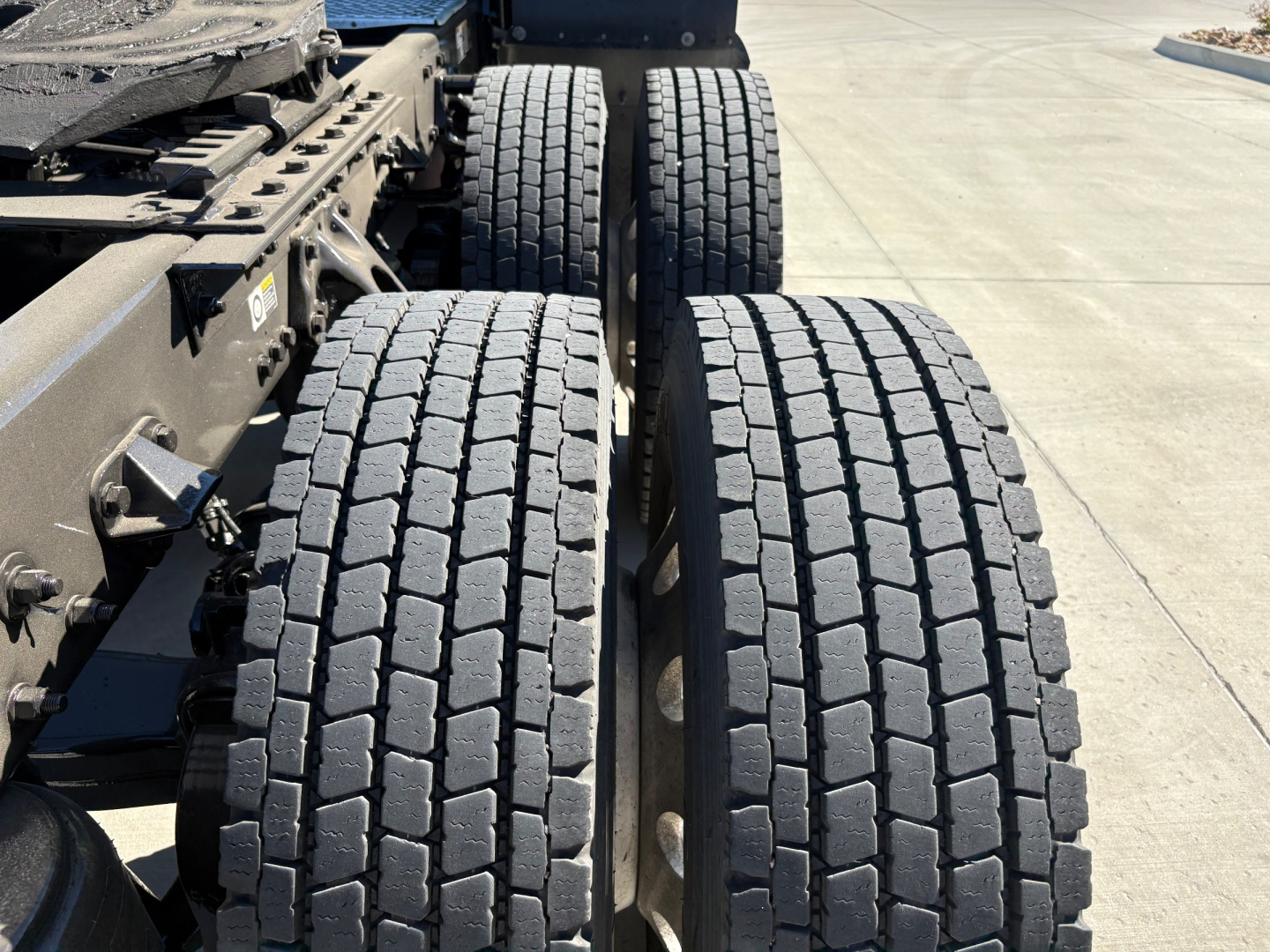 Kenworth T680 truck rear axle area showing dual rear tires with tread, chassis frame, and suspension components.