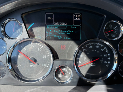 Kenworth truck instrument cluster showing digital trip info screen and gauges with rpm and speed dials in dashboard.