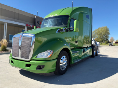 Green 2020 Kenworth T680 semi-truck in front of dealership showing cab, grille, and daytime running lights.