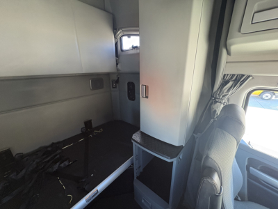 Kenworth T680 cab interior showing sleeper area and dashboard with storage compartments.