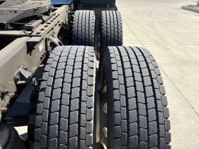Kenworth T680 truck rear axle area showing dual rear tires with tread, chassis frame, and suspension components.