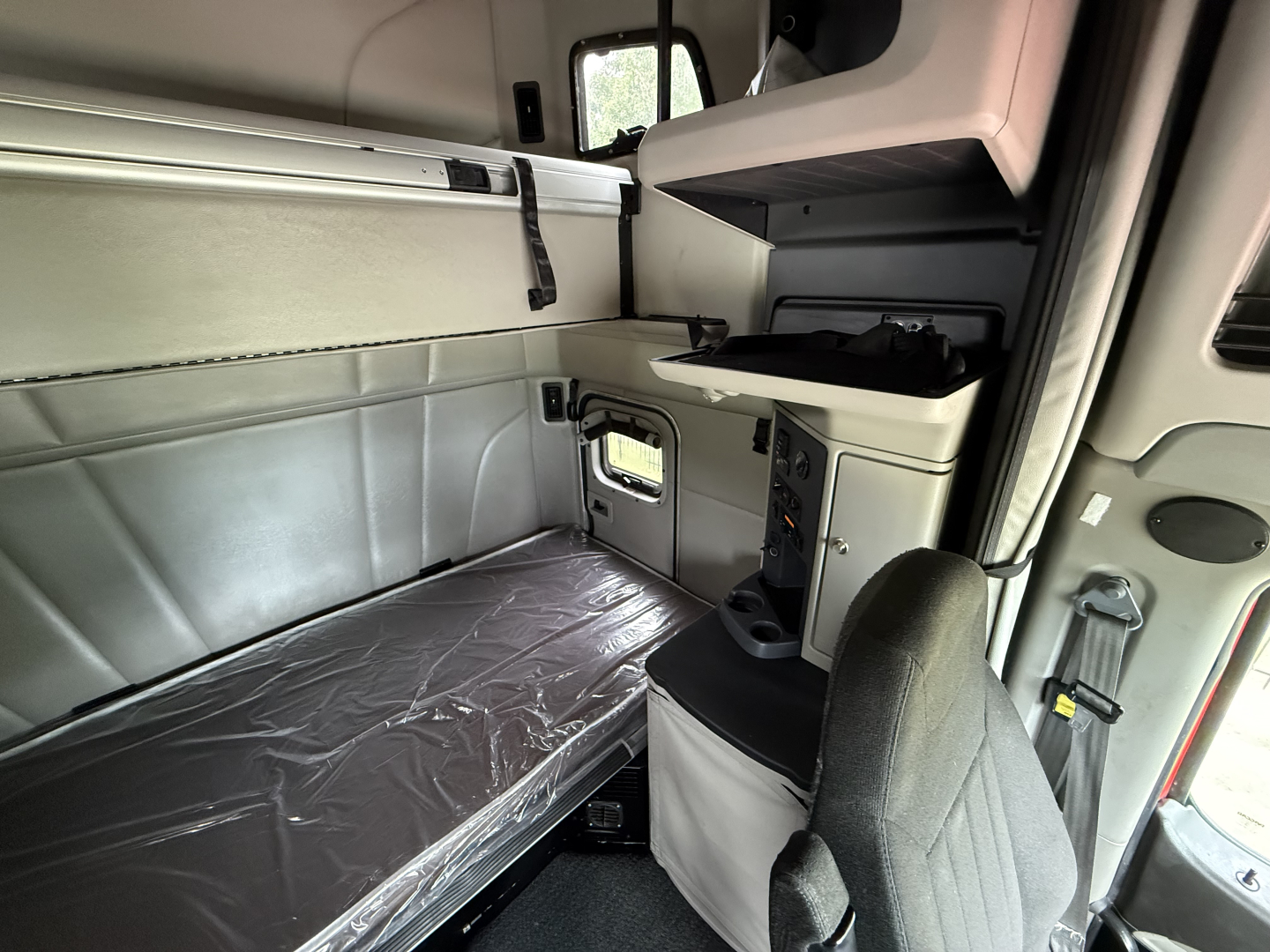Peterbilt 579 truck cabin interior with sleeper berth and passenger seat, side storage cabinets, and window visible.
