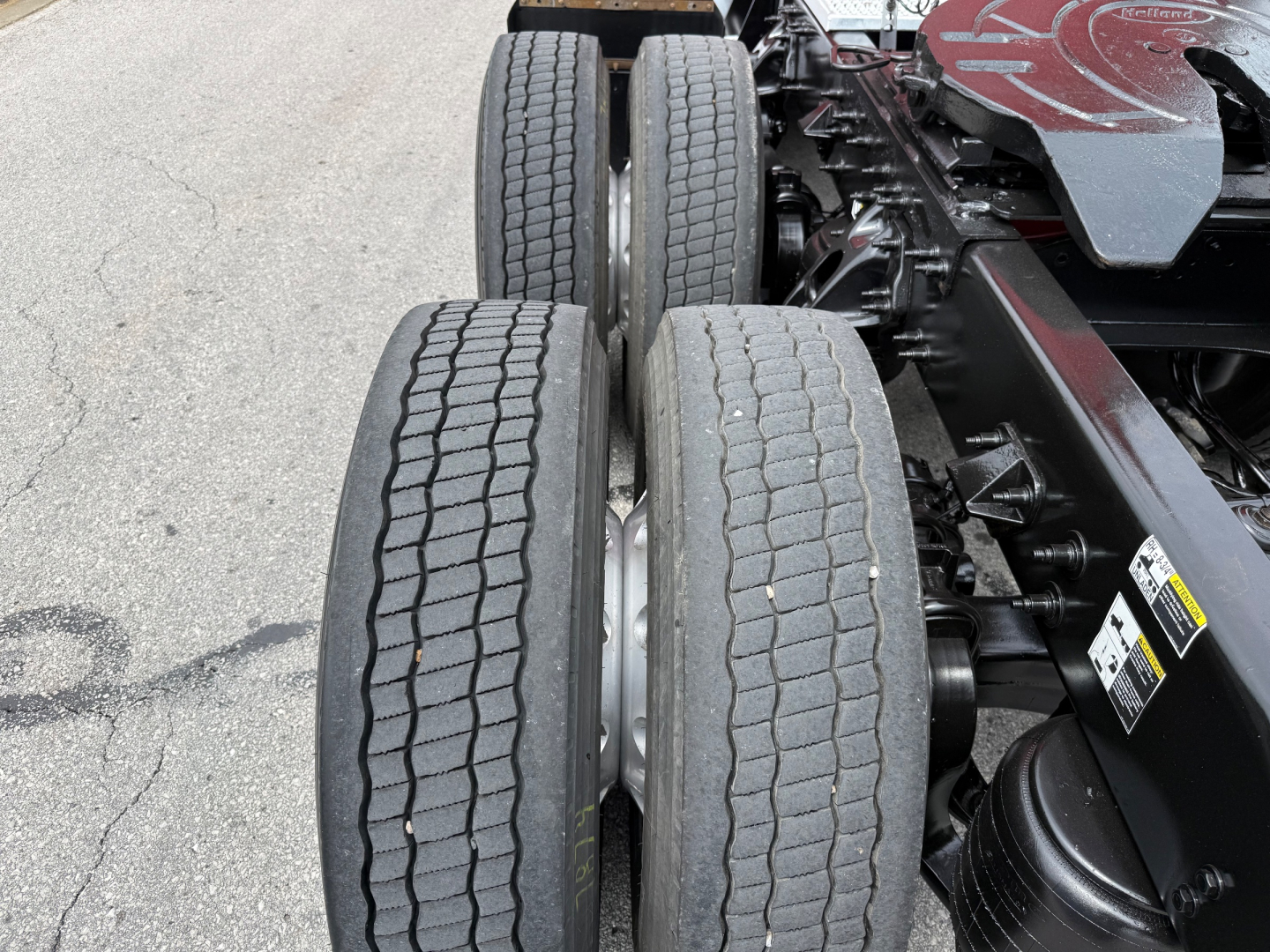 Dual rear axles with tires visible on Peterbilt truck chassis, concrete surface in background.