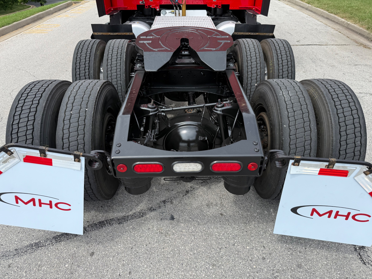 Peterbilt 579 rear chassis and dual axles with six tires visible and mud flaps marked MHC. View shows fifth wheel underframe and rear lighting.