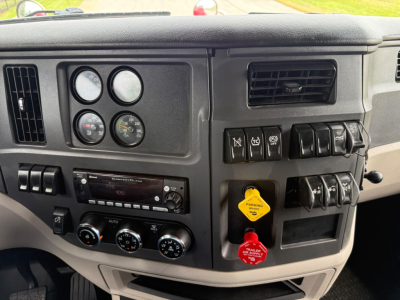 Dashboard of a Peterbilt 579 truck showing multiple gauges, switches, and ignition keys with labels like 'PARKING' yellow tag and red 'HEAVY DUTY' tag.