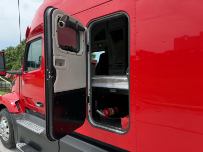 Peterbilt 579 truck cab doorway open showing interior bunk area and step; red exterior, side door open with view into sleeper cab.