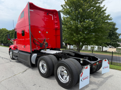 Peterbilt 579 truck rear view showing dual rear axles and sleeper cab in red with chrome wheels and MHC mud flaps.