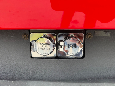 Peterbilt 579 engine bay area showing two chrome fuel heater caps labeled Engine Fuel Heater and Shore Power.