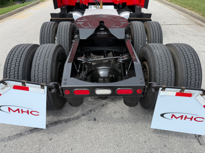 Peterbilt 579 rear chassis and dual axles with six tires visible and mud flaps marked MHC. View shows fifth wheel underframe and rear lighting. 