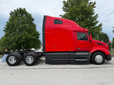 Peterbilt 579 semi truck side profile showing red cab and black lower body with dual rear axles and aluminum wheels.