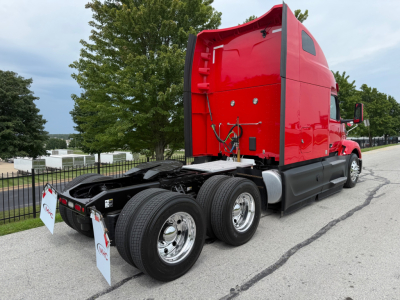 Peterbilt 579 truck tractor with red cab, view of rear and dual rear axles, chrome wheels, fifth wheel area visible, no visible text on cab sides.