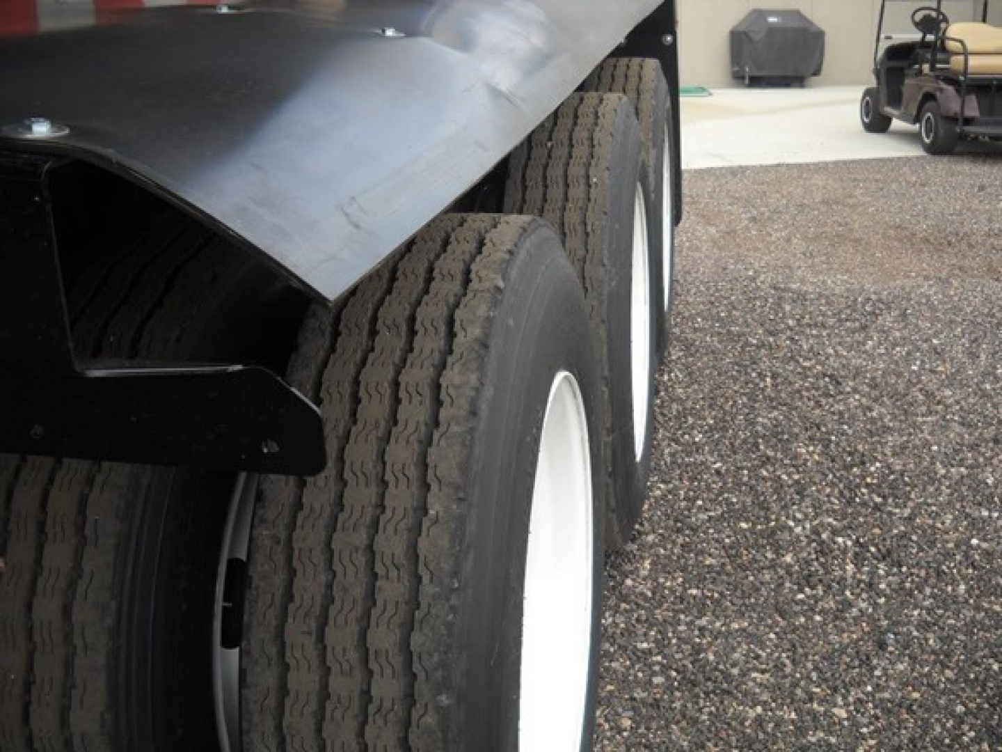 Trailer axle side view showing dual tires and black fender with white wheel rims on a Jet Tri Axle Side Dump.
