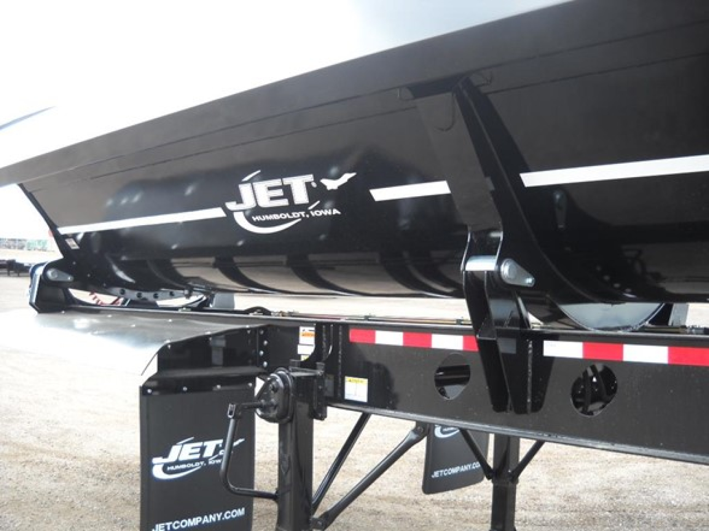 Jet Tri Axle Side Dump trailer showing Jet logo on black dump body and undercarriage frame with reflective tape.