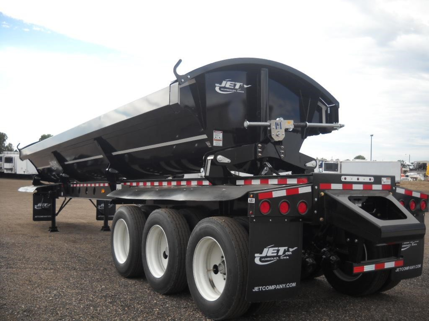 Jet Tri Axle Side Dump trailer showing black dump body with Jet logo, triple axle wheels, and rear tailgate area.