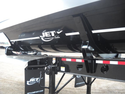 Jet Tri Axle Side Dump trailer showing Jet logo on black dump body and undercarriage frame with support braces and reflective tape.