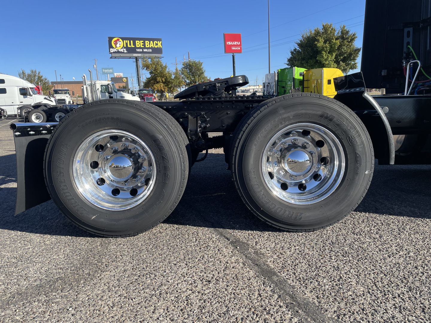 [Component] Dual rear axles with chrome wheels and tires on Volvo VNL64T660 trucks chassis showing suspension, fuel lines, and frame.