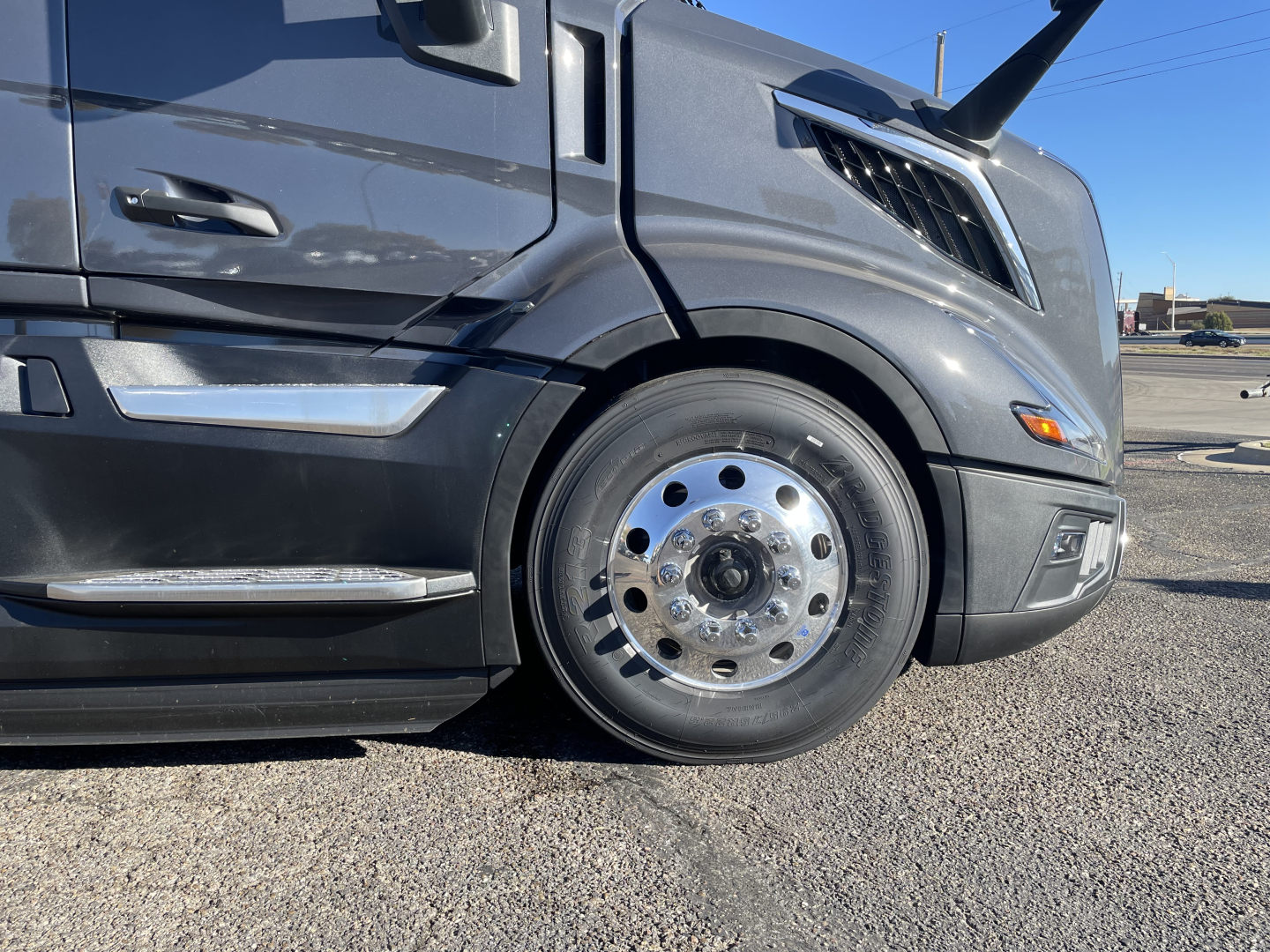 Volvo VNL64T660 tractor cab front wheel and fender with polished aluminum front wheel showing chrome lug nuts.
