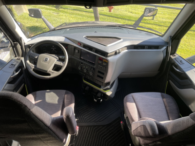 Volvo VNL64T660 cab interior showing steering wheel, dashboard, center console with screen, and driver + passenger seats.