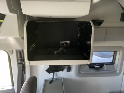 Truck cab storage compartment open with USB power port visible inside. Surrounding panels and window in sleeper cab of a Volvo VNL series.