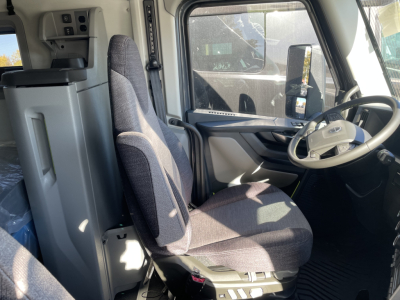 Driver seat and dashboard of a Volvo VNL64T660 truck cab showing steering wheel, driver's seat, window, and dash controls.