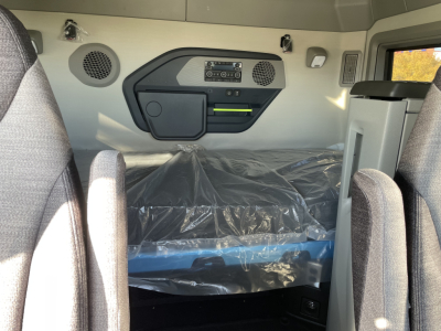 Volvo VNL64T660 sleeper cab interior showing control panel, storage pocket, two speaker grilles, and plastic-covered bunk area.