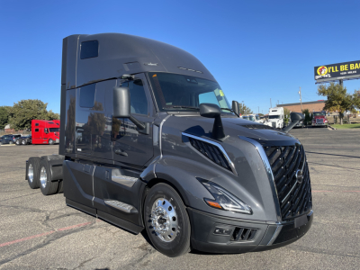Volvo VNL64T660 truck in service bay showing aerodynamic black exterior and chrome wheels.