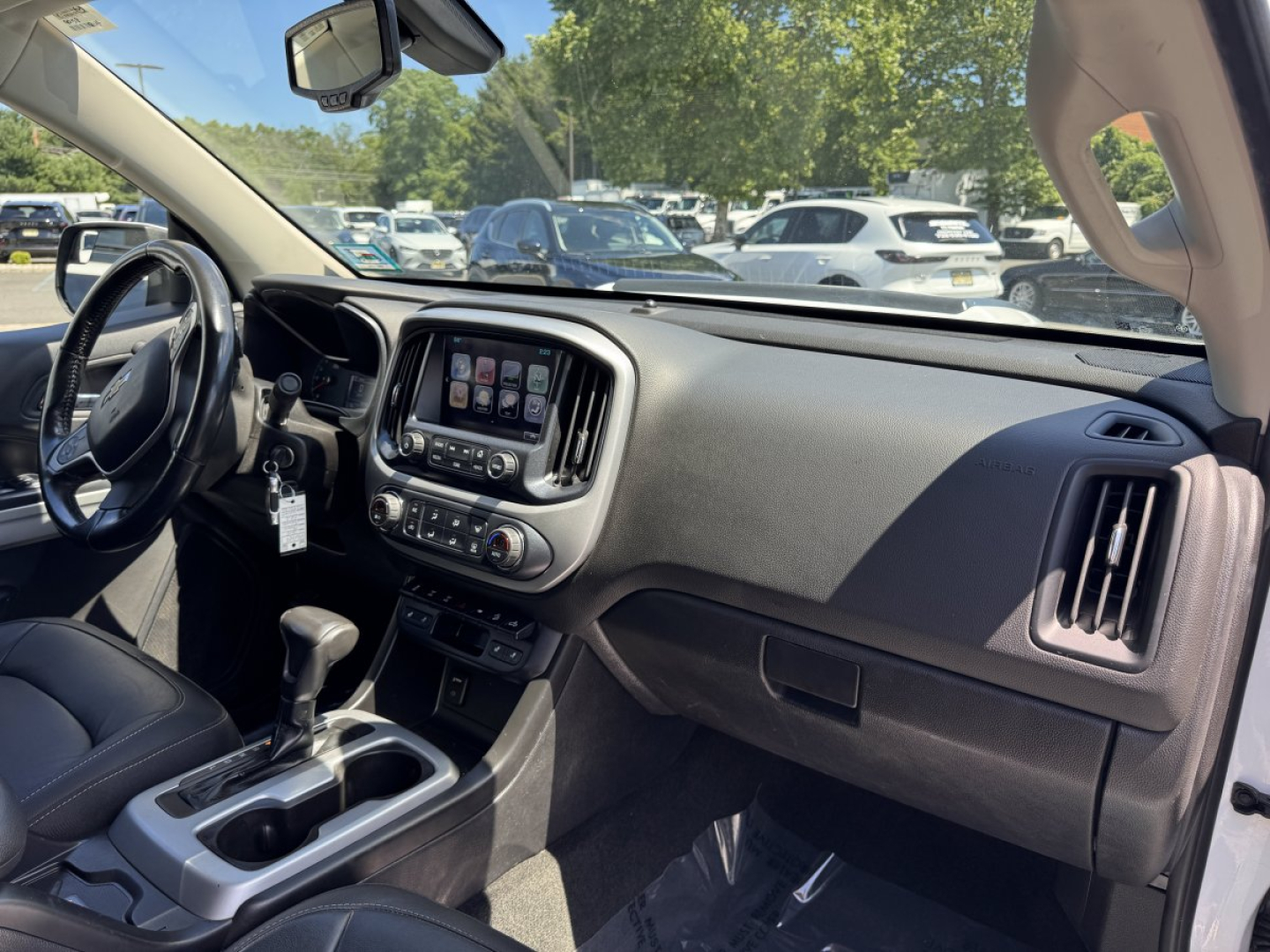 Interior of a 2018 Chevrolet Colorado pickup truck showing dashboard, steering wheel, center touchscreen, gear shifter, and front passenger area.